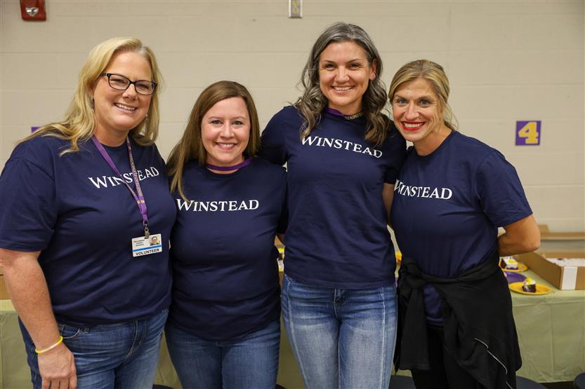 Four teachers stand and smile